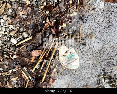 An FFP2 mask lies in the water on the bank Stock Photo