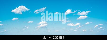Panorama sky and clouds. White cumulus clouds on clear blue sky background closeup, overcast skies backdrop, fluffy cloud texture, sunny cloudscape he Stock Photo