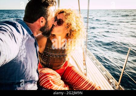 Adult beautiful married couple kissing on the yacht on vacation - romantic travel tour excursion with man and woman together with love - honeymoon and luxury lifestyle Stock Photo