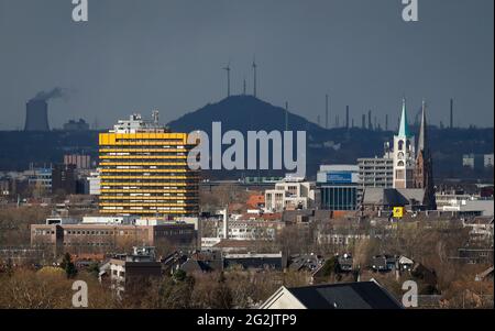 Gelsenkirchen, North Rhine-Westphalia, Germany - City overview of Gelsenkirchen with the old town church in front of a dark sky, in the back the Oberscholven heap and Uniper power station Scholven. Stock Photo