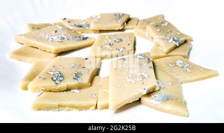 Kaju Katli is a Diamond shape Indian sweet made using cashew sugar and mava, served in a plate isolated on white background. selective focus Stock Photo