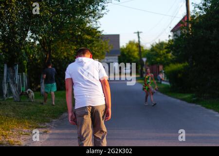 Defocus girl and boy playing on skateboard in the street. View from back. Caucasian kids riding penny board, practicing skateboard. Friendship fun con Stock Photo