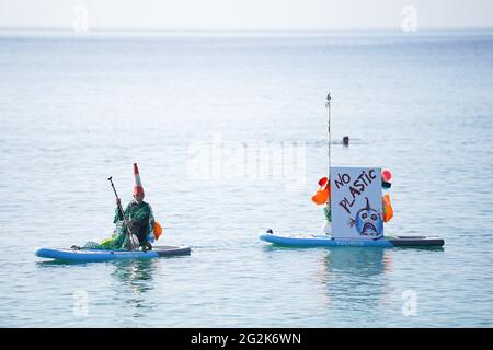 A climate protester sits on a paddle board in the sea off Swanpool Beach near Falmouth during the G7 summit in Cornwall. Picture date: Saturday June 12, 2021. Stock Photo