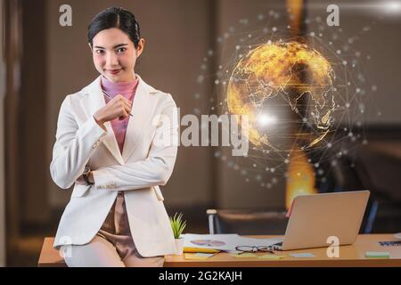 Portrait Asian businesswoman standing and smiling in modern office over Particle earth with technology network background, Business and technology con Stock Photo