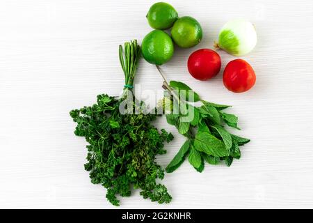 bundles and mint packets with lemons, tomatoes and onion on white wooden textured background Stock Photo