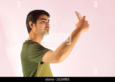 Young handsome Indian man taking selfie with mobile phone. Stock Photo