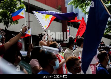 Metro Manila, Philippines. 12th June 2021. Activists carry signs and Philippine flags as they gather to protest in front of the Chinese consulate marking Independence Day in the financial district of Makati. Various groups called on China to stop its maritime activities in the disputed South China Sea, which endangers peace and stability in the region. Credit: Majority World CIC/Alamy Live News