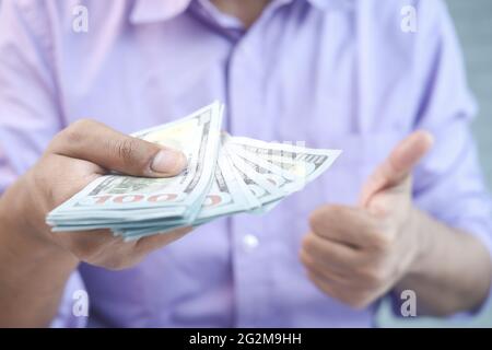 Close up of man holding us dollar and showing thumbs up  Stock Photo