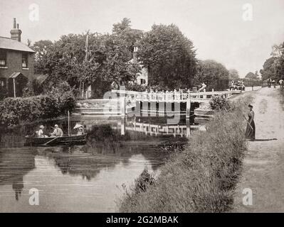 A late 19th century view of people in a rowing boat below Sonning Lock, a lock and associated weir situated on the River Thames at the village of Sonning near Reading, Berkshire, England. The first lock was built by the Thames Navigation Commission in 1773 and it has been rebuilt three times since then, the last time being 1868. Stock Photo