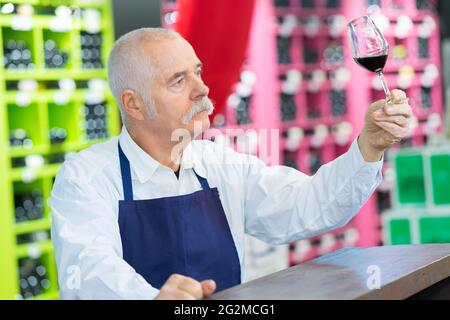 senior man inspecting glass of red wine Stock Photo