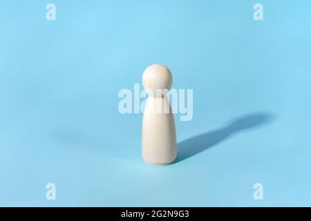 Abstract concept of lonely person. Minimalist, wooden figure with shadow on blue Stock Photo