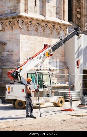 Milan, Italy - July 7, 2020. Construction worker on duty standing close to crane. Duomo cathedral building during reconstruction, building facade Stock Photo