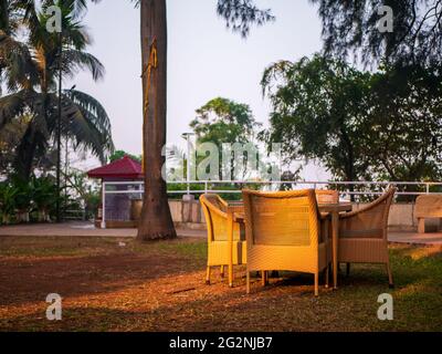 MUMBAI, INDIA - December 31, 2021:Wooden weave chair and table in the lawn with sun light in the morning Stock Photo