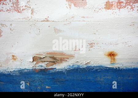Textured backdrop of rugged wall with blue and white paints with blots on uneven surface Stock Photo