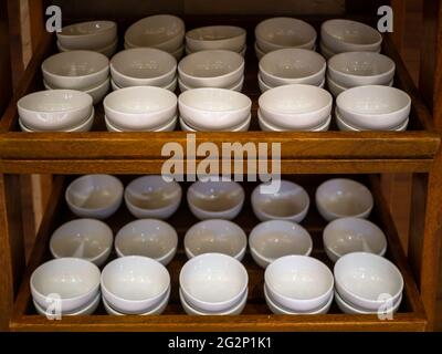 cleaned white bowls arranged neatly on wooden furniture Stock Photo
