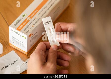 A woman looking at a negative test result after taking a self diagnostic VivaDiag SARS-CoV-2 Ag Rapid Test for Covid-19 at home Stock Photo