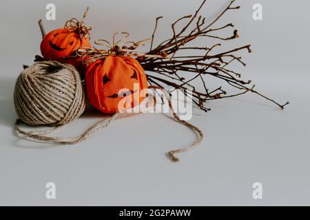 Closeup of the decorative Halloween pumpkins made out of fabric with some twigs on the white surface Stock Photo