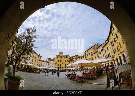 Lucca, Italy - May 23, 2021: view of piazza dell’anfiteatro (amphiteater square) in Lucca, Italy, ring shaped square with tuscan restaurants, tables, Stock Photo