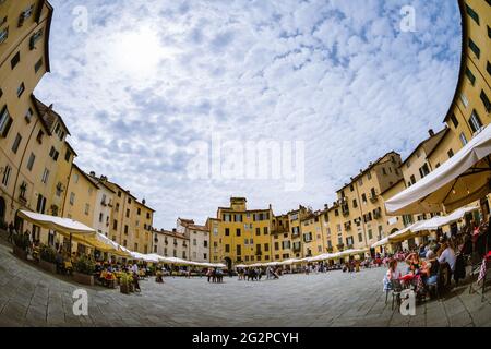 Lucca, Italy - May 23, 2021: view of piazza dell’anfiteatro (amphiteater square) in Lucca, Italy, ring shaped square with tuscan restaurants, tables, Stock Photo