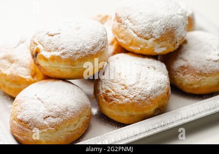 Berliner Pfannkuchen, a German donut, traditional yeast dough deep fried filled with chocolate cream and sprinkled with powdered sugar, sweetness on a Stock Photo