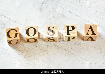 Five wooden cubes with letters GOSPA (stands for Goals Objectives Strategies Plans Activities) on white stone like board, view from above Stock Photo