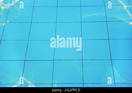 Azure blue swimming pool old tiled floor, sun reflects on ground, underwater photo - abstract holiday background Stock Photo