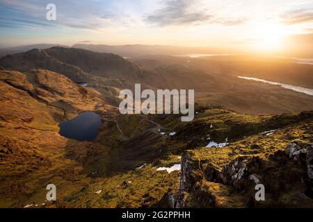 Golden sunrise overlooking epic view of Lake District mountains from the Old Man of Coniston. Stock Photo