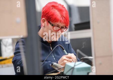Industrial worker woman soldering cables of manufacturing equipment in a factory Stock Photo