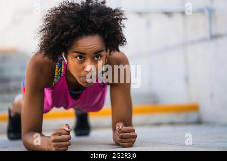 Afro athlete woman doing pushups outdoors. Stock Photo
