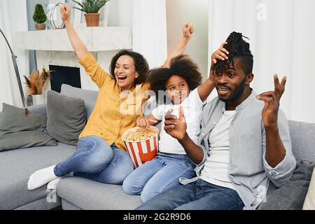 Positive family enjoys time together and watching a fun tv show with popcorn. Happy family togetherness Stock Photo