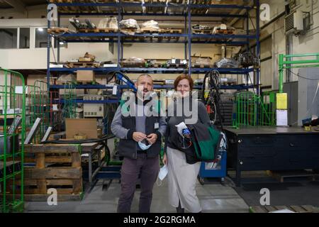 Industrial workers with face masks protected against corona virus discussing about production in factory. People working during COVID-19 pandemic. Stock Photo