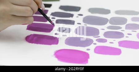 Women hand holds a brush with paint and draws on a white sheet circles  Stock Photo