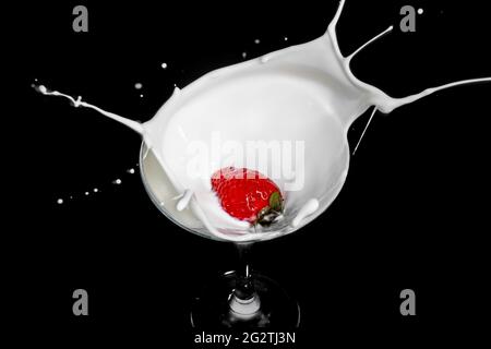 Fresh strawberry falling into glass of milk with a splash Stock Photo