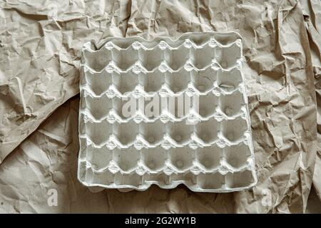 Close up of empty egg tray on background of crumpled paper. The concept of recycling, reuse. Stock Photo