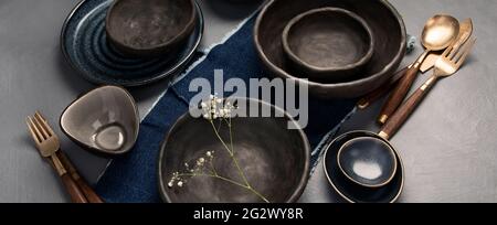 Table setting with a black and blue plates on gray background. Minimalism concept. Stock Photo