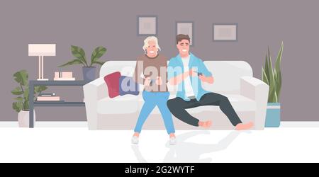 couple sitting on sofa using joysticks man woman playing video games together during coronavirus pandemic Stock Vector