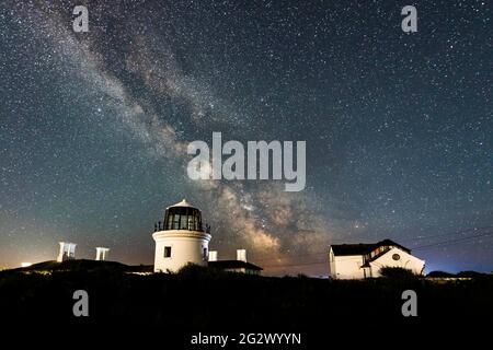 Portland Bill, Dorset, UK.  13th June 2021.  UK Weather.   The Milky Way glows brightly in the clear night sky above the higher lighthouse at Portland Bill in Dorset.  Picture Credit: Graham Hunt/Alamy Live News