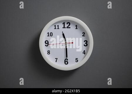 A white clock hangs on a gray wall. Stock Photo