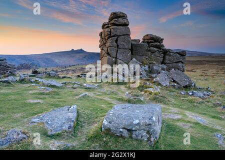 The photograph features rocks on Hound Tor in the Dartmoor National Park in Devon captured at sunrise with Haytor in the distance. Stock Photo