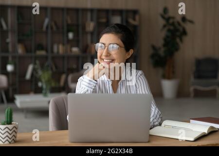 Indian lady scientist work on laptop think distracted from screen Stock Photo