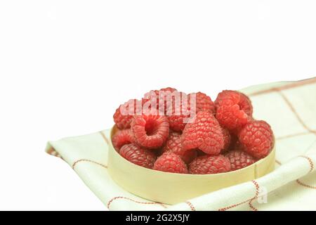 Raspberries are fresh and juicy on a wooden background. Ripe raspberries in a basket on a wooden table. Close-up, background with space for text. Harv Stock Photo