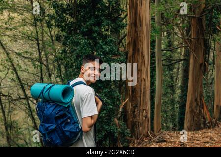 smiling young man with backpack doing trekking or hiking Stock Photo