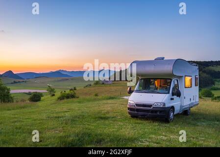 Sunset clear sky over camper van in Montelago highlands, Marche, Italy. Traveling road trip in unique hills and mountains landscape, alternative vanli Stock Photo