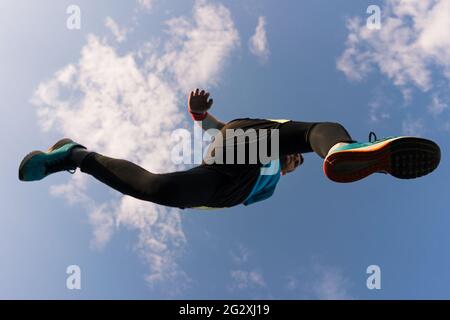 Low angle view of a sportsman who jump and run with blue sky in background Stock Photo