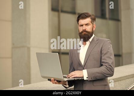 Web conferencing. Serious engineer use laptop outdoors. Computer conference. Making video call. Video conference. Modern technology. Formal fashion Stock Photo