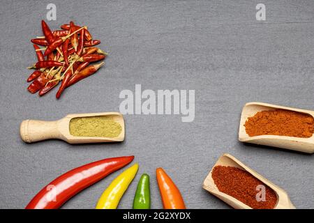 Top view of multicolored fresh chilli peppers and dried and ground chilli on the desk.Horizontally. Stock Photo