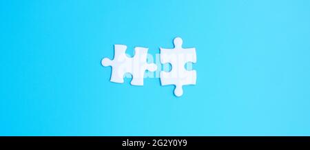 couple of white puzzle jigsaw pieces on blue background. Concept of solutions, mission, success, goals, cooperation, partnership, strategy and puzzle Stock Photo