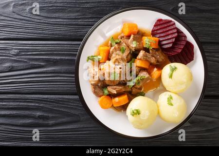 Swedish Kalops, an authentic and traditional beef stew slow simmered with vegetables close up in the plate on the table. horizontal top view from abov Stock Photo