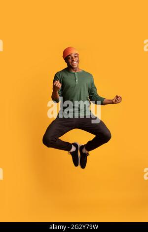 Excited Happy African American Guy Celebrating Success While Jumping In Air Stock Photo