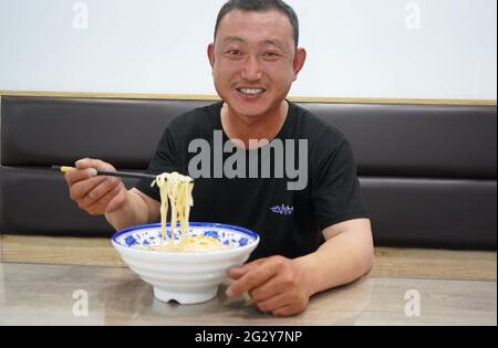(210613) -- XINGTAI, June 13, 2021 (Xinhua) -- Local farmer Su Chuan has noodles as the day's meal in Xingtai, north China's Hebei Province, June 9, 2021. With the summer wheat harvest underway, farmers in north China's Xingtai have been busy in the fields to reap the year's premium grains. In Xingtai, a total of 65 farmers have joined the Jinshahe specialized cooperative that provides them with technical guidance in crop harvesting. The cooperative will sell freshly harvested crops to a local noodle factory where staple products are made and sold to customers. (Xinhua/Jin Haoyuan) Stock Photo